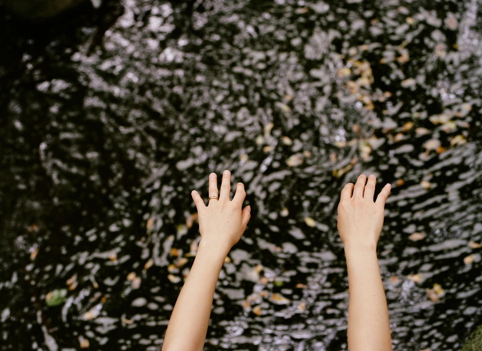 Hands reaching toward rippling water